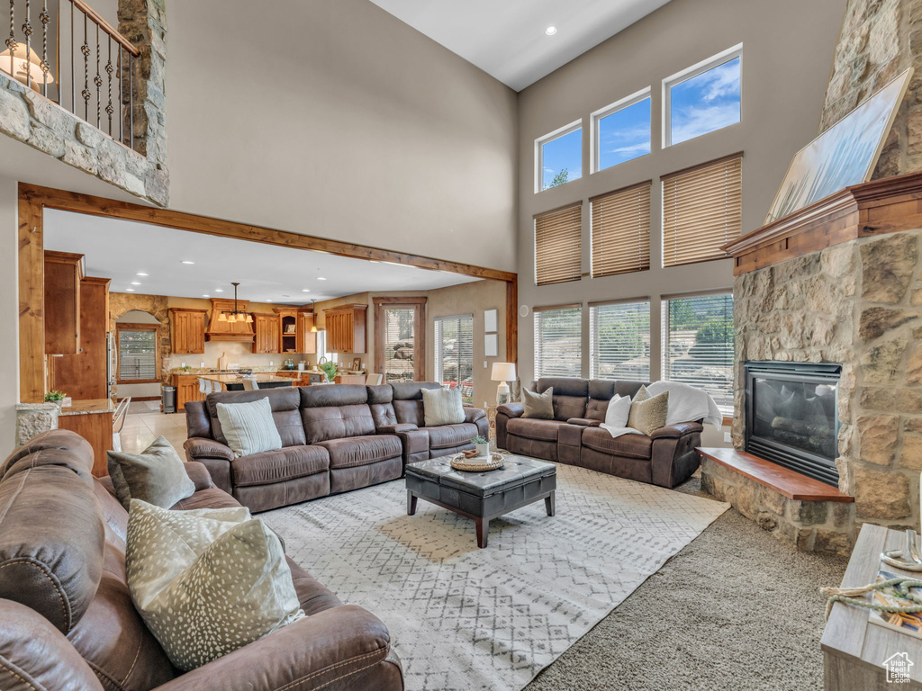 Living room featuring a towering ceiling, recessed lighting, a fireplace, and light carpet