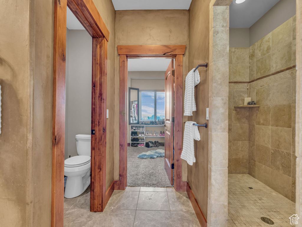 Full bath with a tile shower, toilet, and tile patterned floors