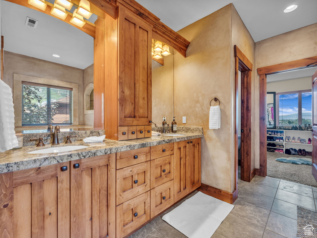 Bathroom with healthy amount of natural light, double vanity, baseboards, and recessed lighting