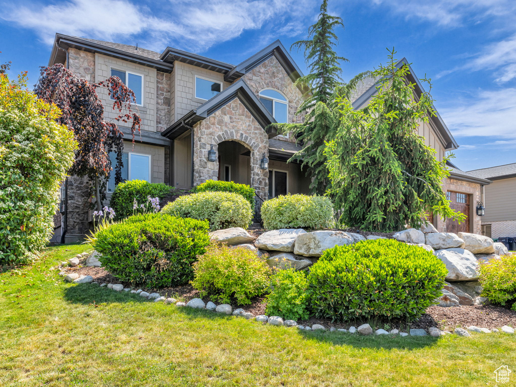 View of front of home featuring stone siding and a front yard
