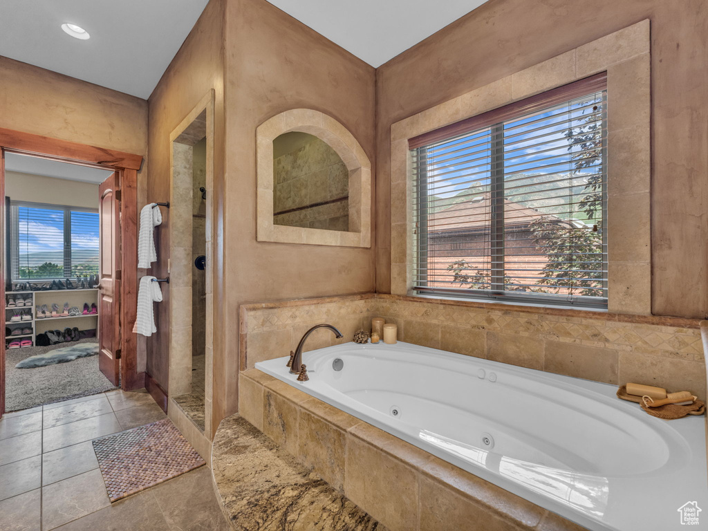 Bathroom featuring plenty of natural light, a tub with jets, a stall shower, and tile patterned flooring