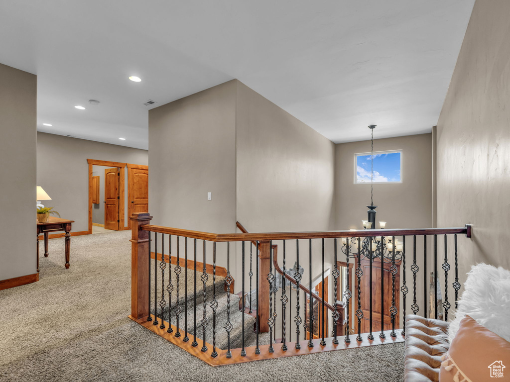 Hallway with an upstairs landing, carpet, baseboards, recessed lighting, and a chandelier