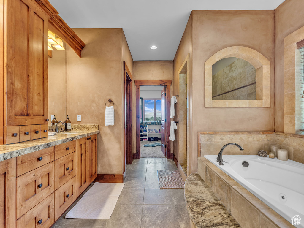 Bathroom featuring connected bathroom, a tub with jets, vanity, baseboards, and recessed lighting