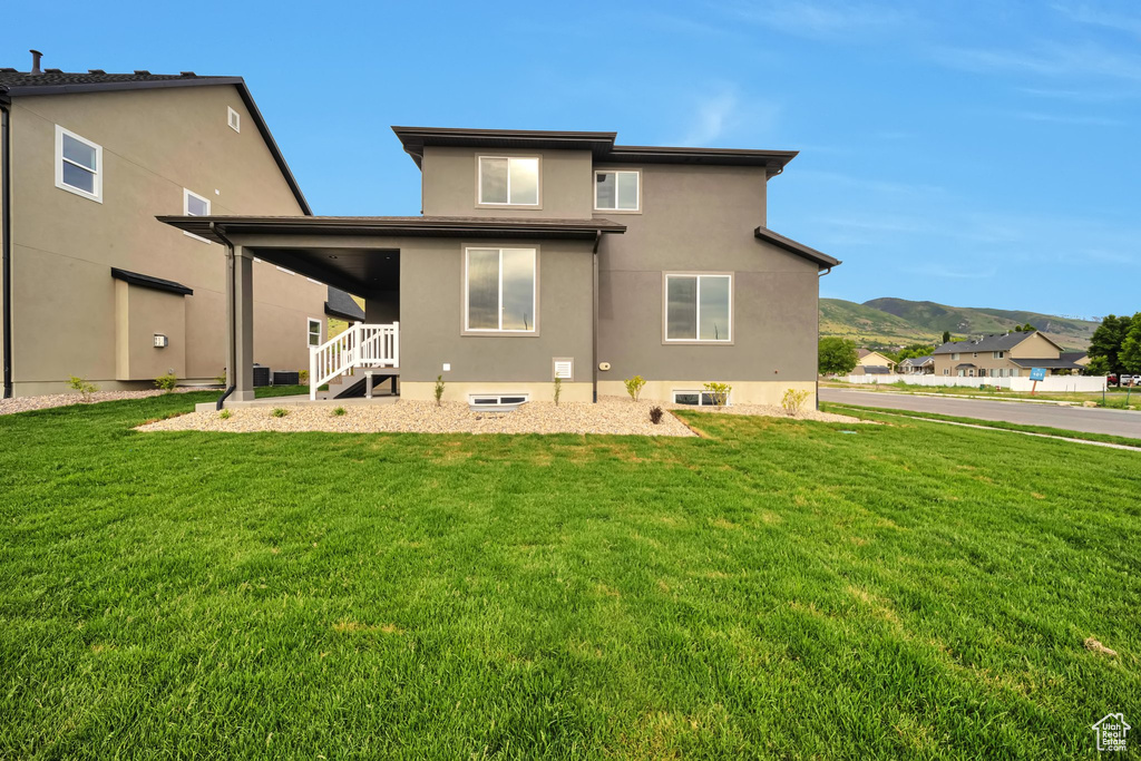 Back of property with a lawn, stucco siding, and a mountain view