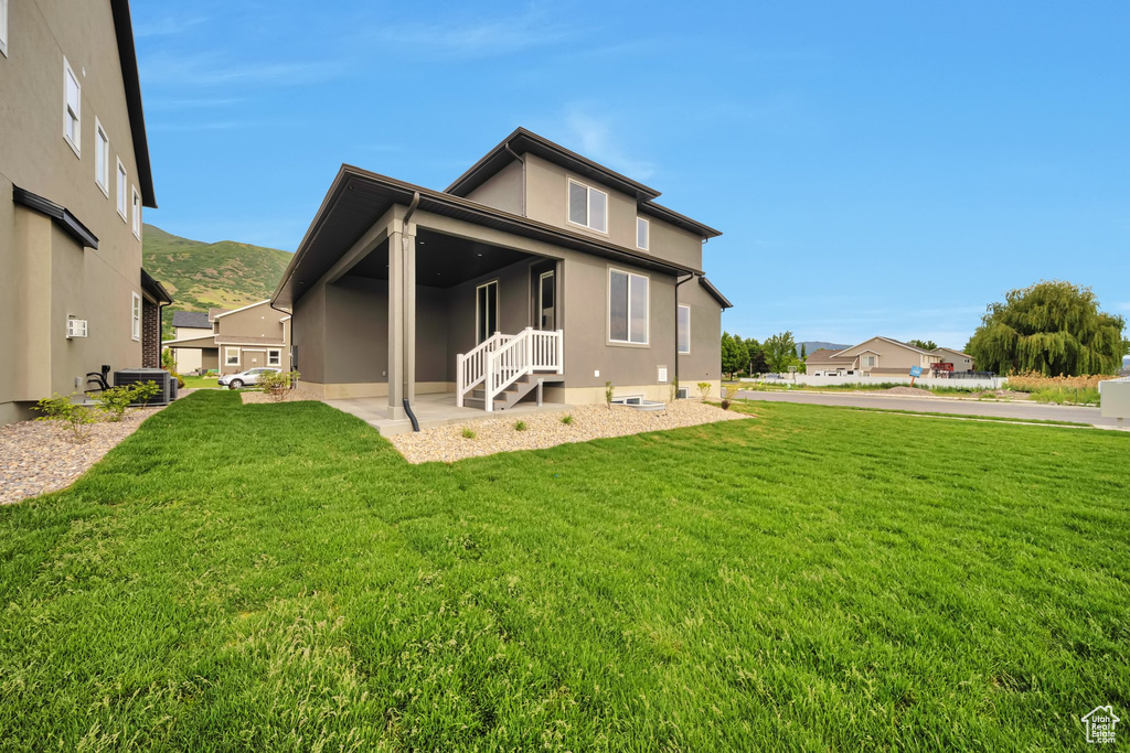 Back of property with a lawn, stucco siding, and central AC unit