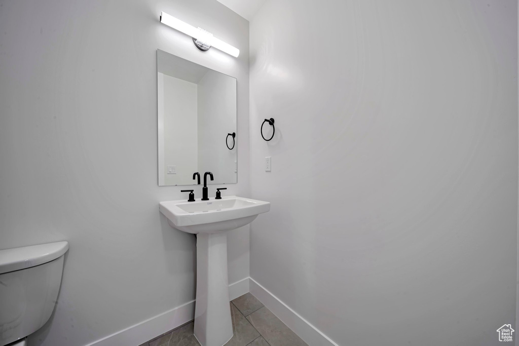 Bathroom featuring baseboards, toilet, and tile patterned flooring