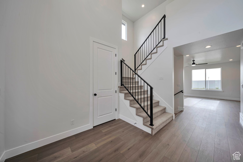 Stairs featuring ceiling fan, wood finished floors, baseboards, recessed lighting, and a towering ceiling