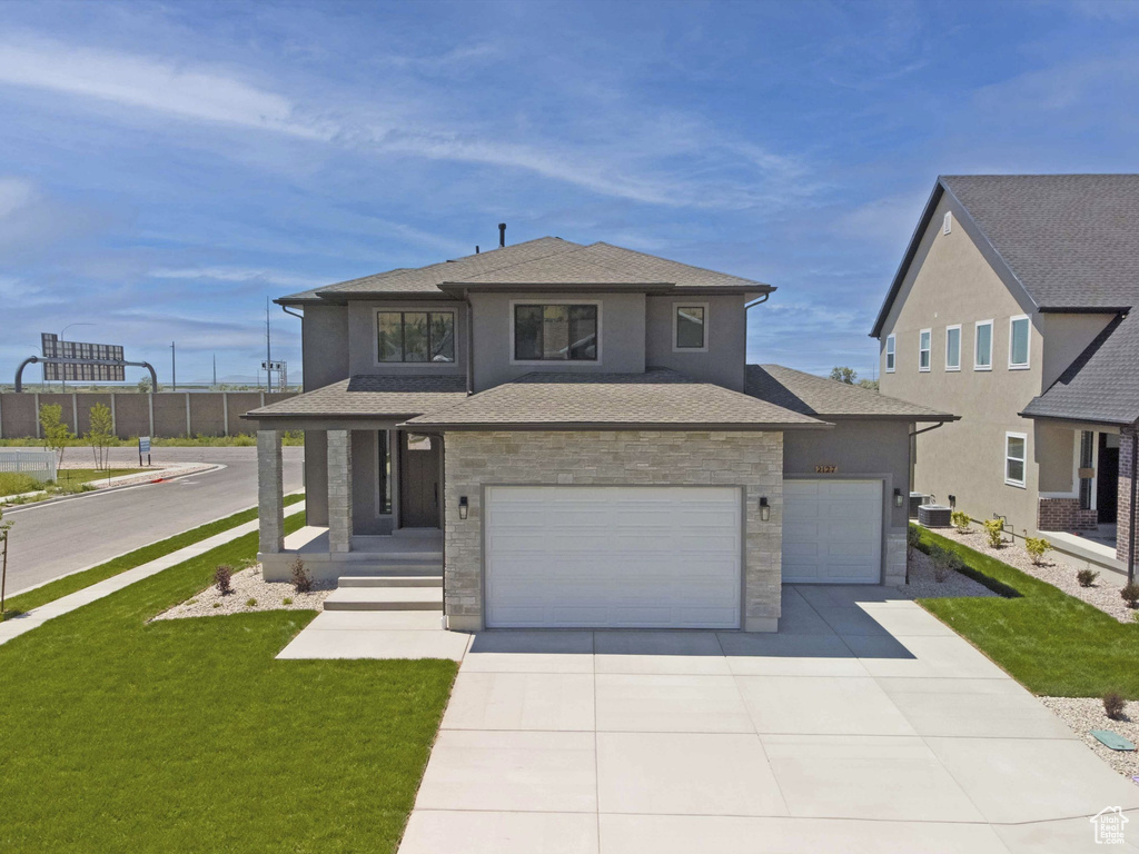 View of front of house featuring concrete driveway, stone siding, stucco siding, a shingled roof, and a garage