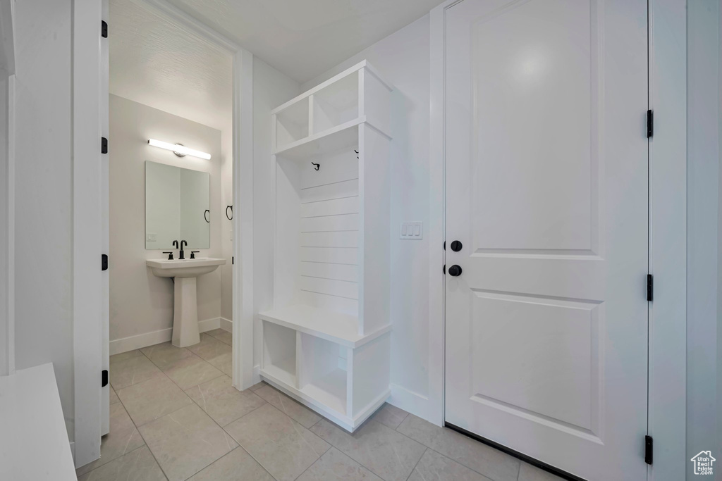Mudroom featuring baseboards, light tile patterned floors, and a sink