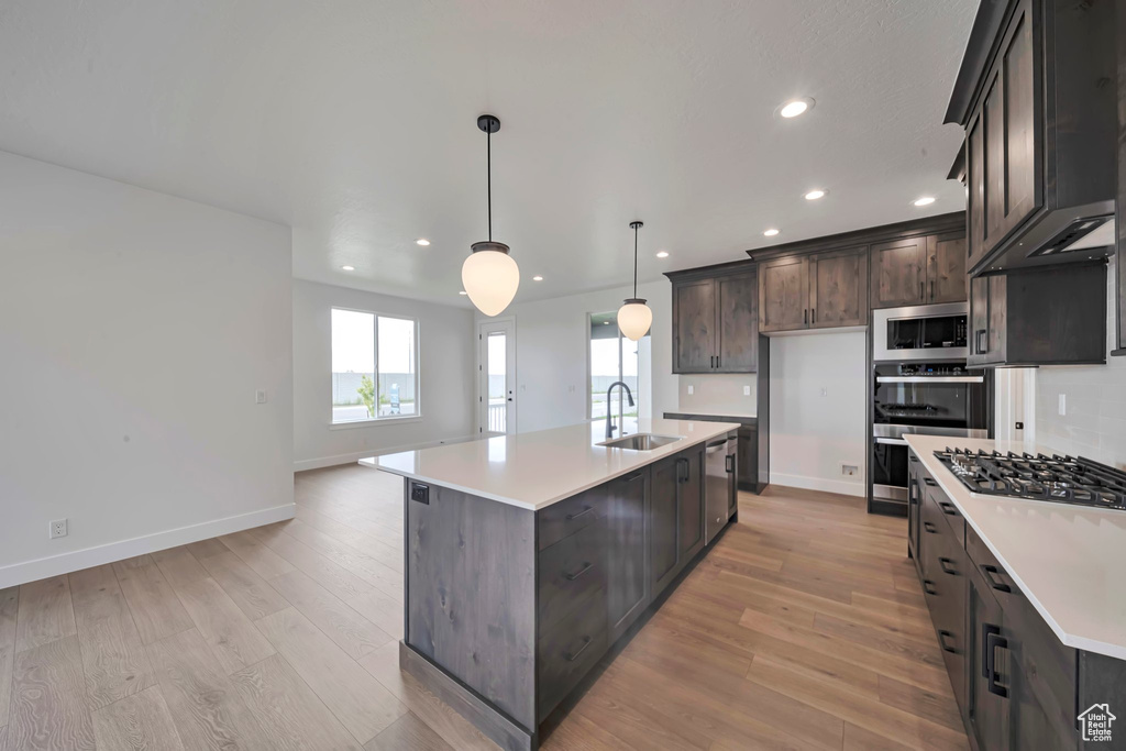 Kitchen featuring a sink, stainless steel appliances, recessed lighting, light wood finished floors, and light countertops