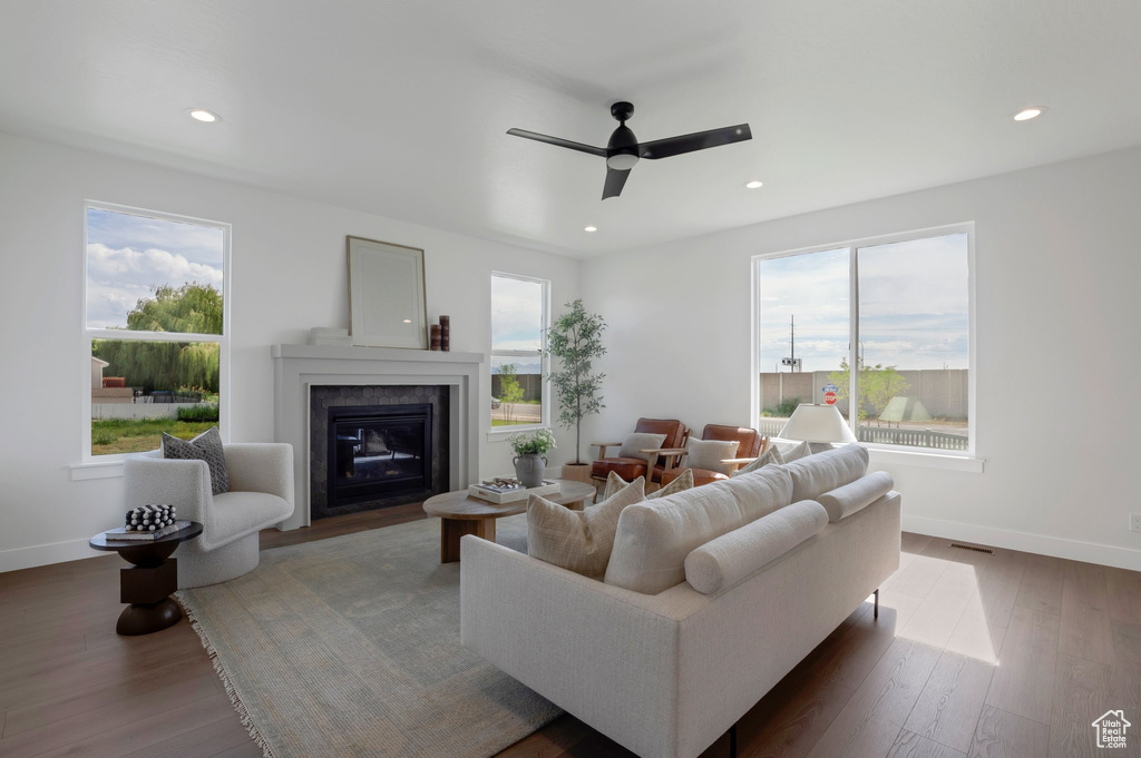 Living room with a fireplace with flush hearth, ceiling fan, wood finished floors, and recessed lighting