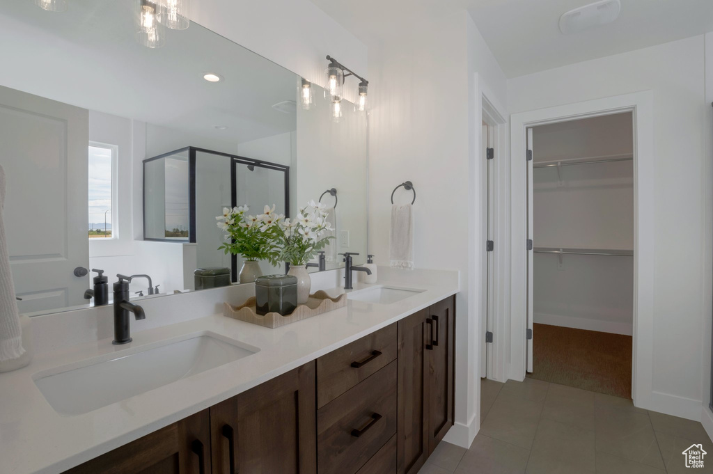Bathroom featuring a spacious closet, double vanity, a stall shower, tile patterned floors, and recessed lighting