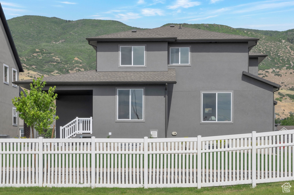 Rear view of house featuring a mountain view, stucco siding, and a shingled roof