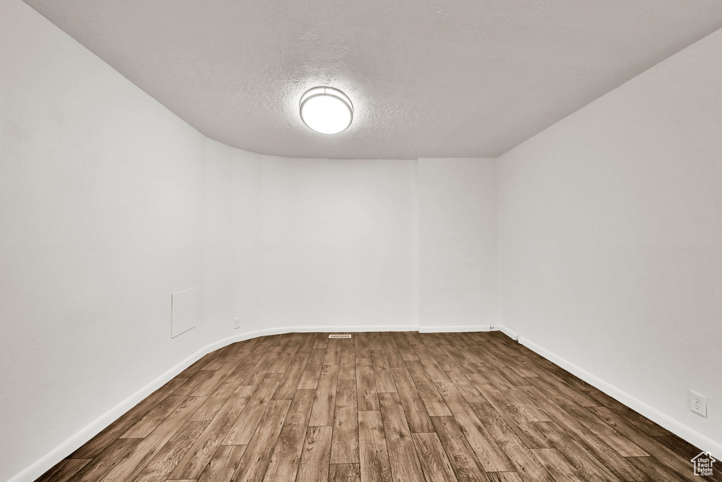 Spare room with wood finished floors, a textured ceiling, and baseboards