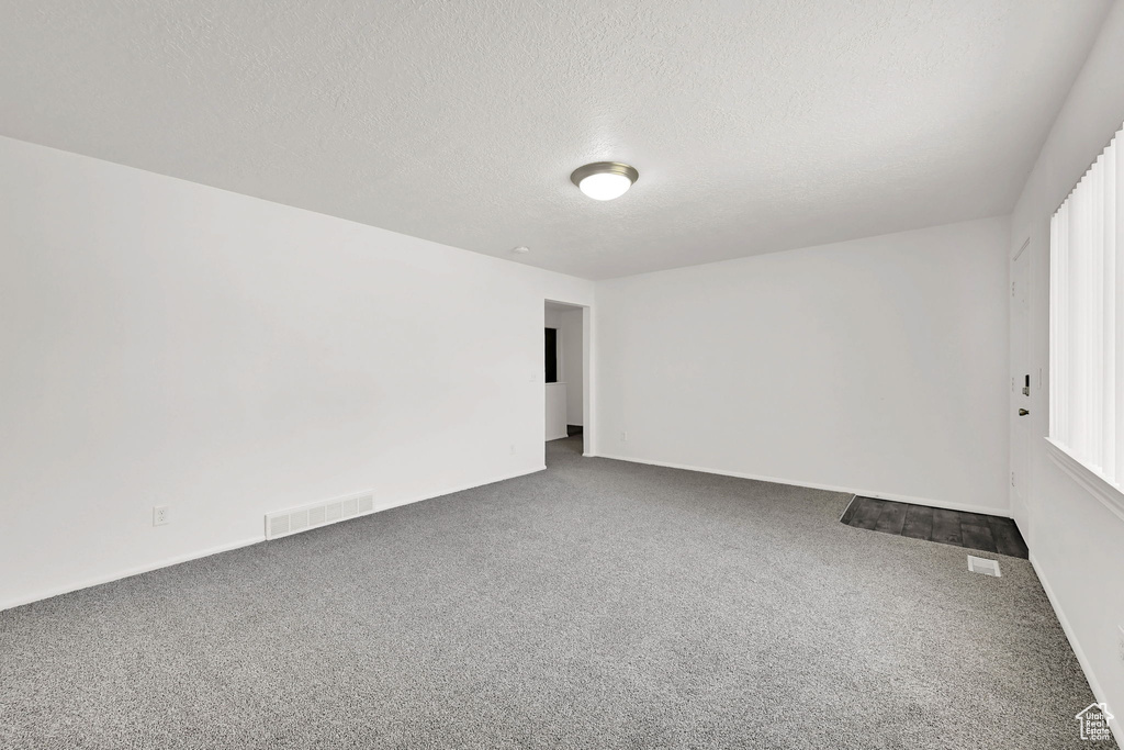 Carpeted empty room featuring a textured ceiling
