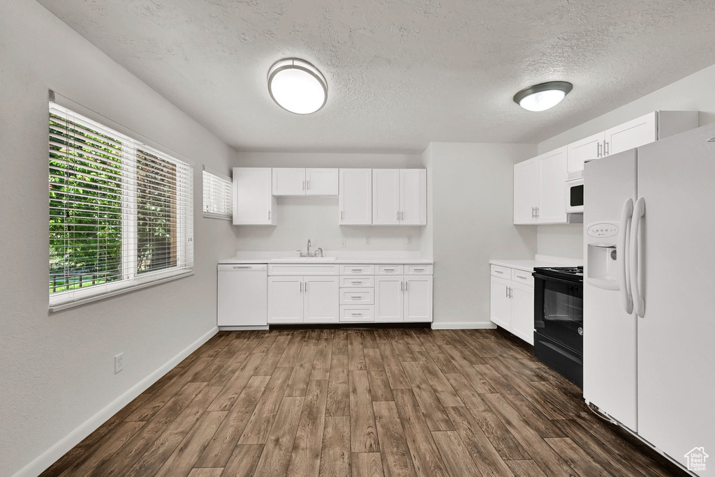 Kitchen with white appliances, a sink, light countertops, white cabinets, and a textured ceiling