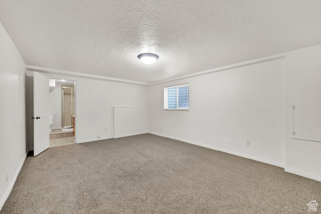 Carpeted spare room with a textured ceiling and baseboards