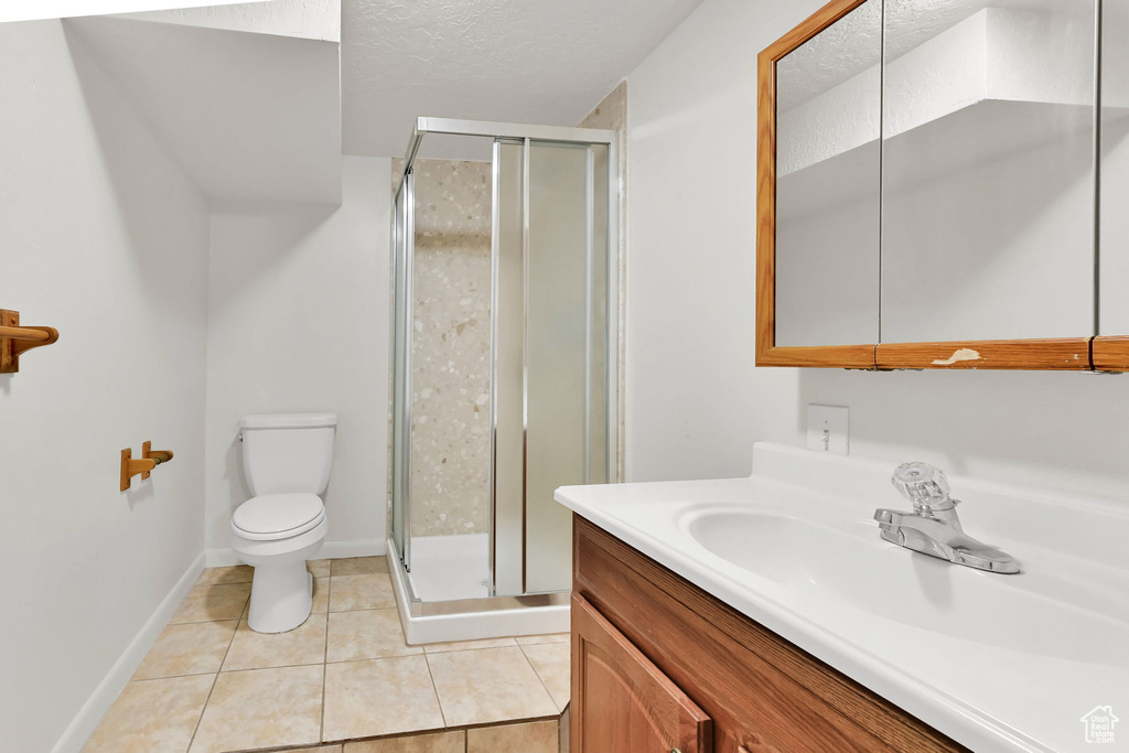 Full bathroom featuring vanity, toilet, a stall shower, tile patterned floors, and a textured ceiling