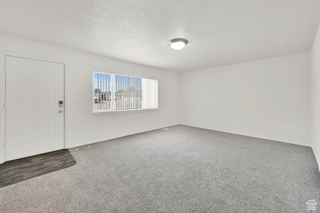 Carpeted entrance foyer with a textured ceiling and baseboards