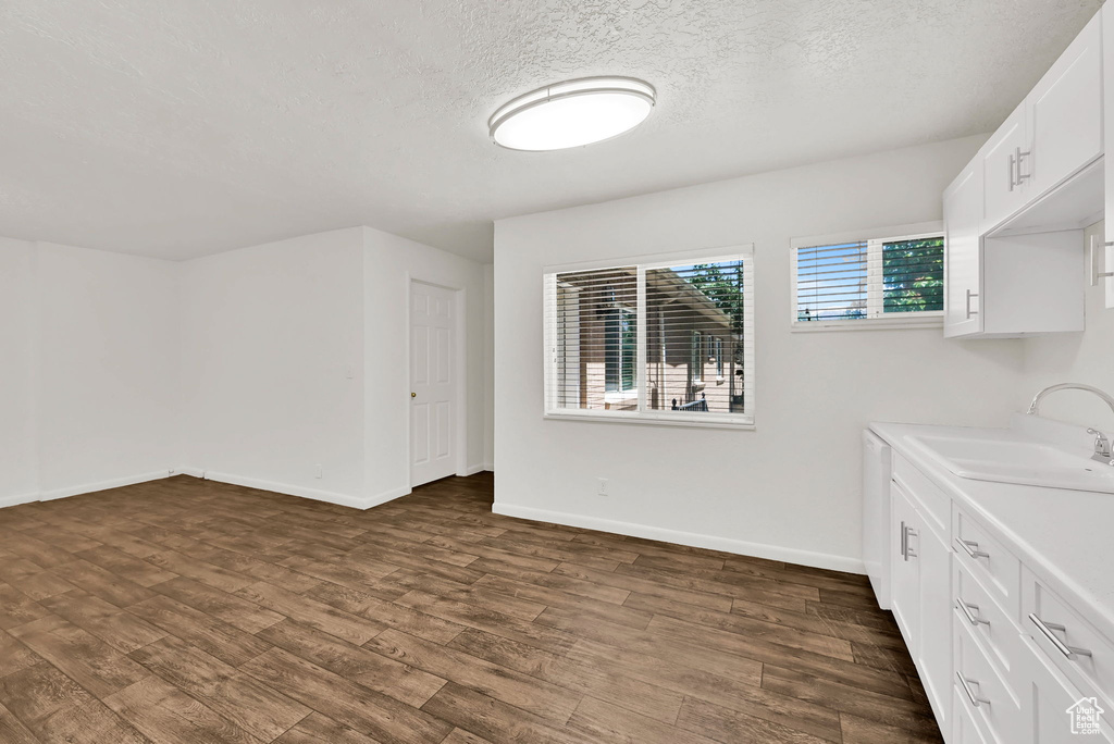 Laundry area with a sink, dark wood-type flooring, baseboards, and a textured ceiling