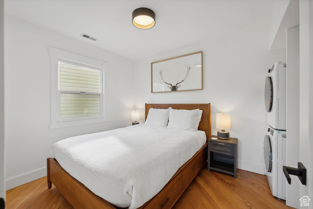Bedroom with estacked washer and dryer, baseboards, and light wood finished floors