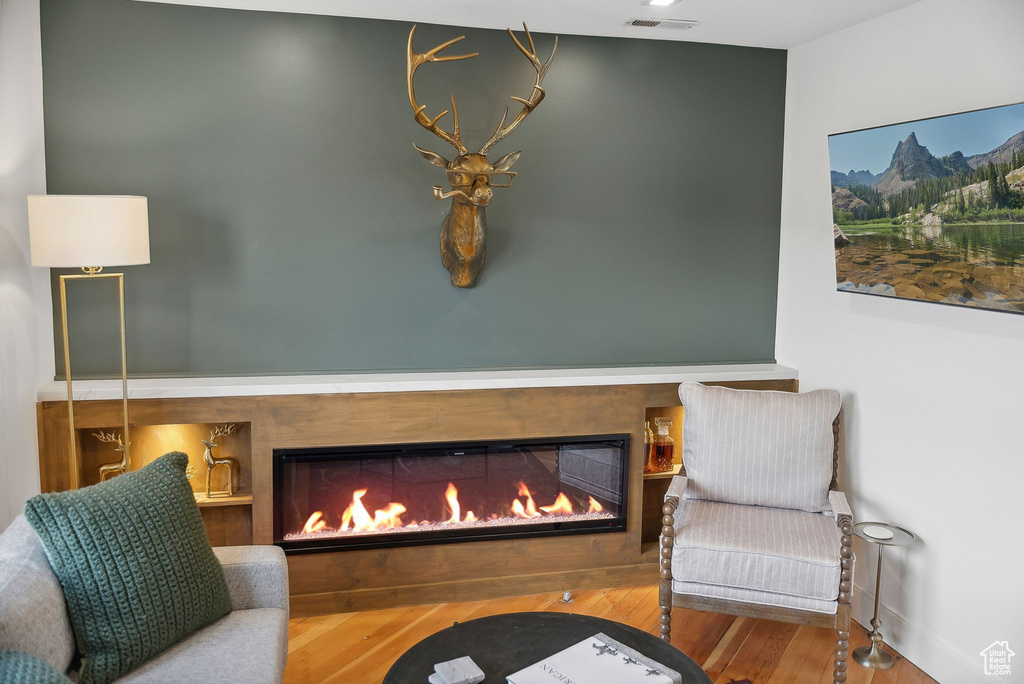 Sitting room with a warm lit fireplace, wood finished floors, and baseboards