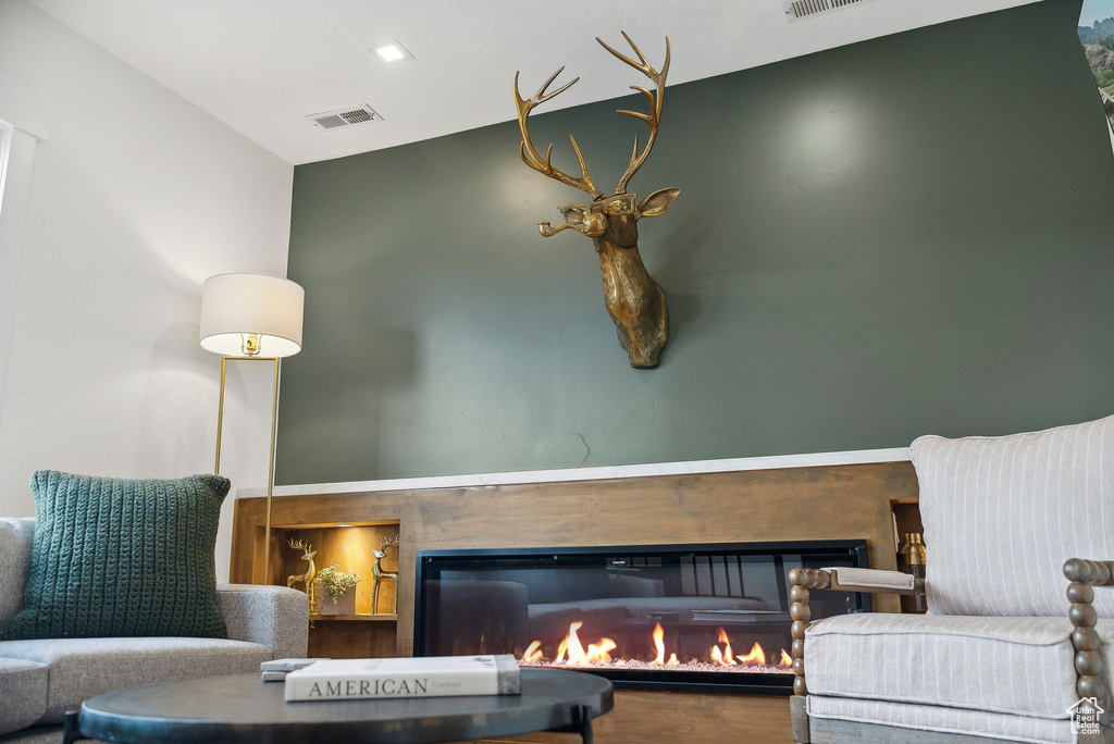 Sitting room featuring a glass covered fireplace and wood finished floors