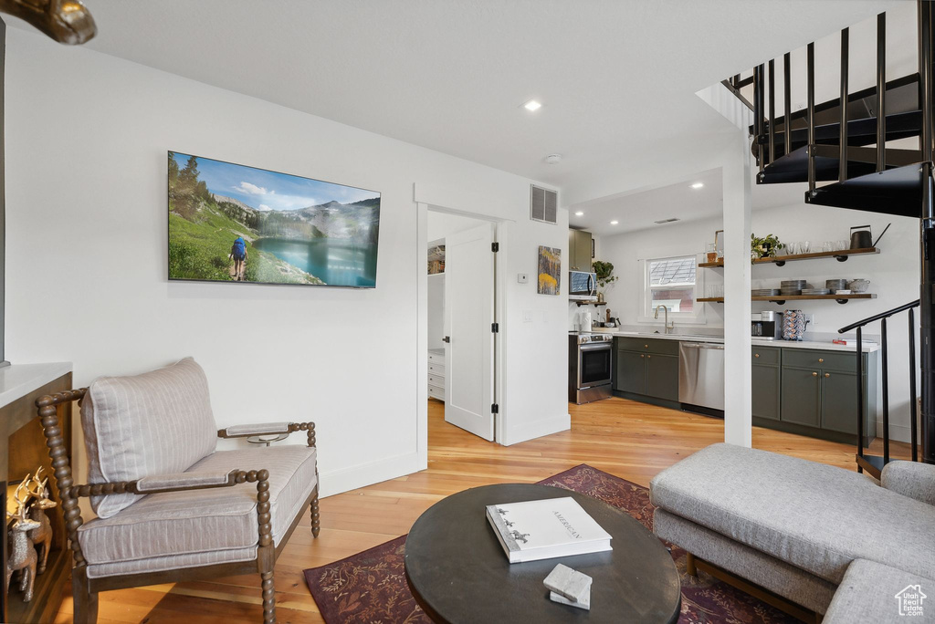 Living room featuring light wood-style floors, recessed lighting, and stairway