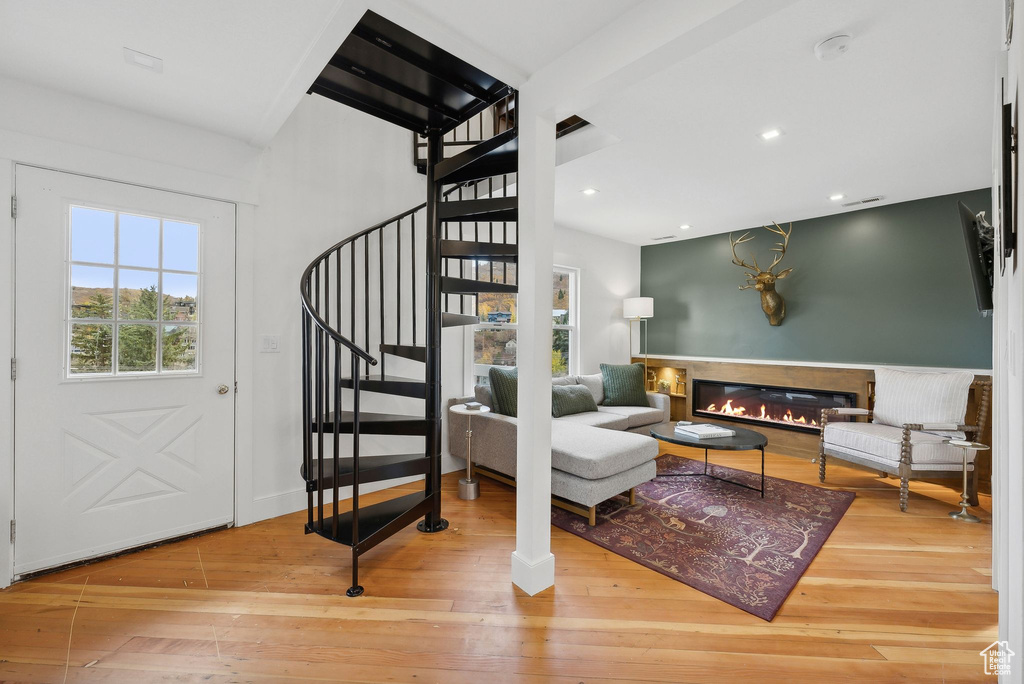 Living room with stairway, hardwood / wood-style floors, a glass covered fireplace, and recessed lighting