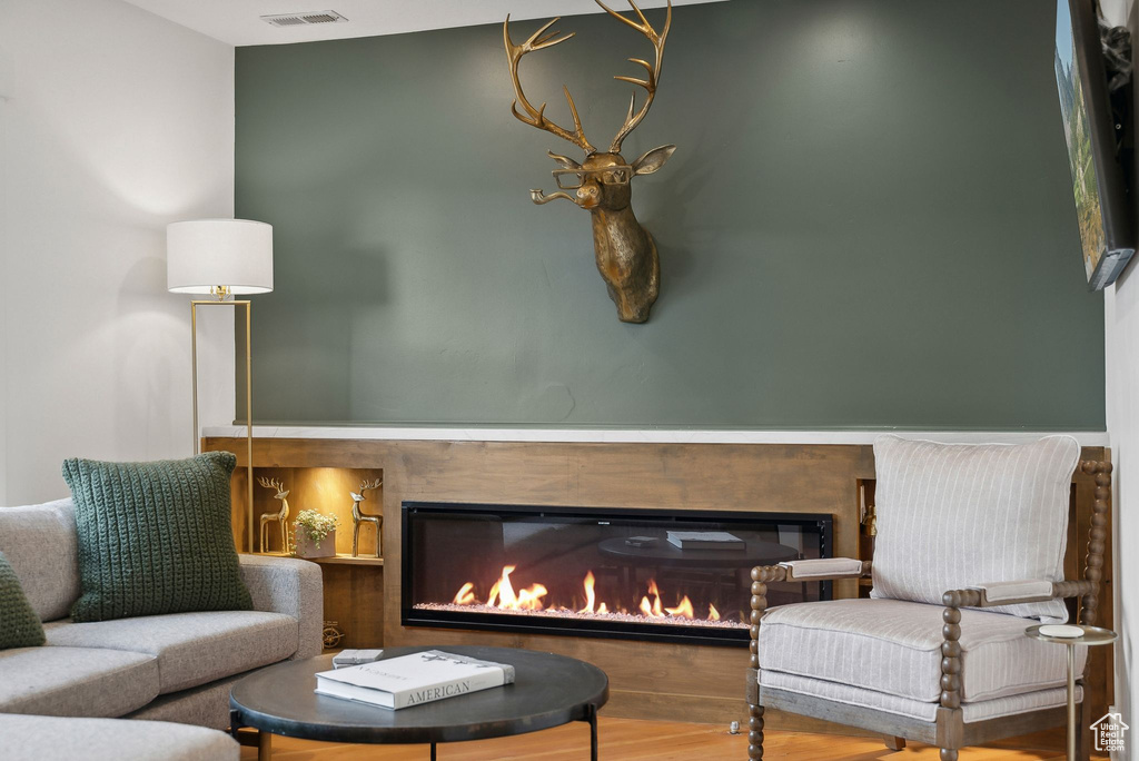 Sitting room featuring wood finished floors and a glass covered fireplace