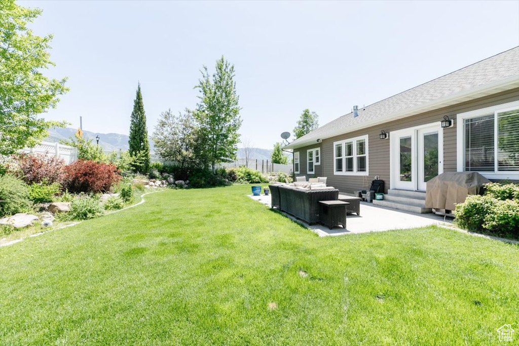 View of grassy yard featuring an outdoor living space, a patio area, a mountain view, and entry steps