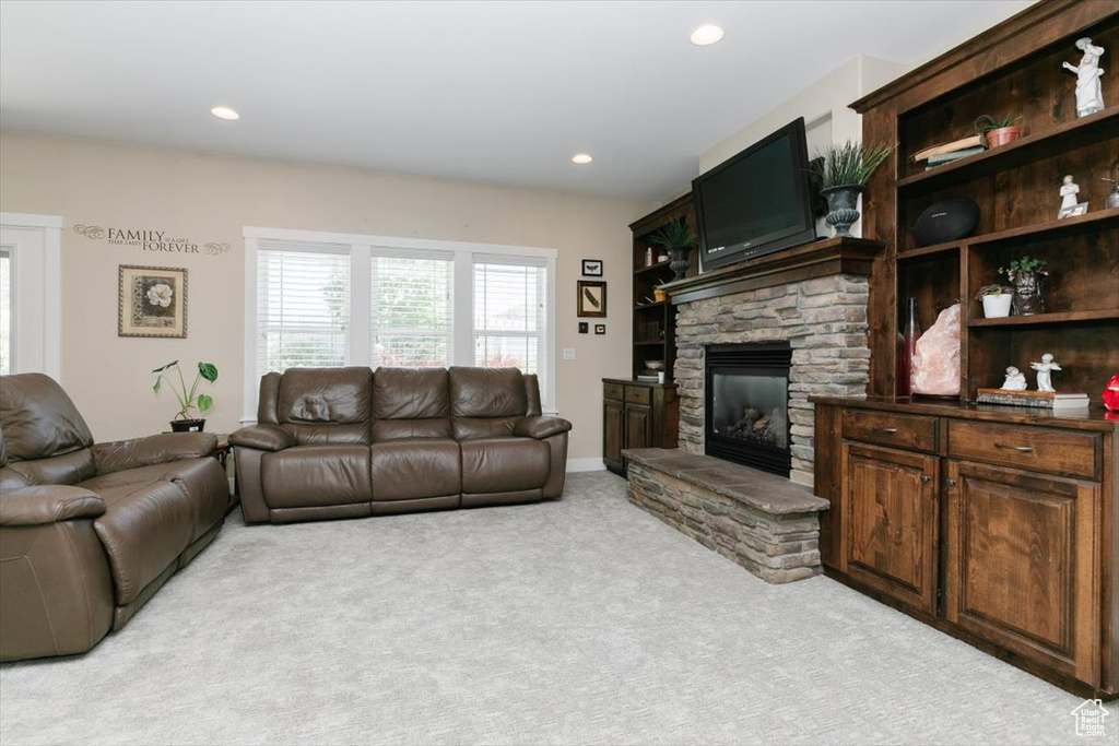 Living area with light colored carpet, a stone fireplace, and recessed lighting