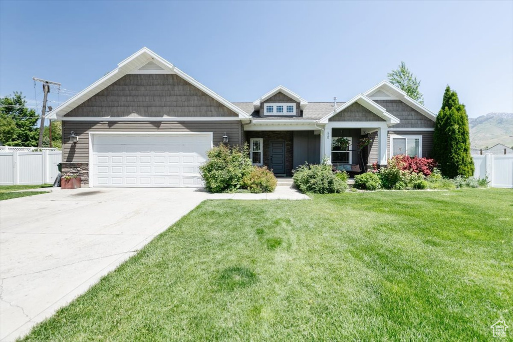 Craftsman house featuring an attached garage, driveway, and stone siding