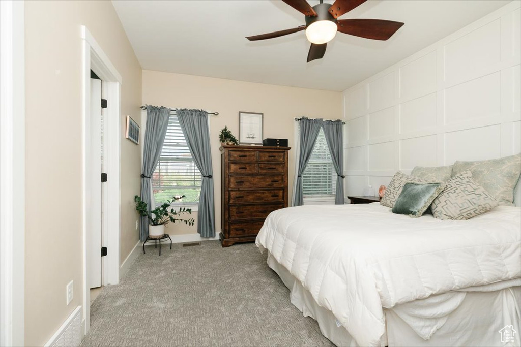 Bedroom with light colored carpet and a ceiling fan