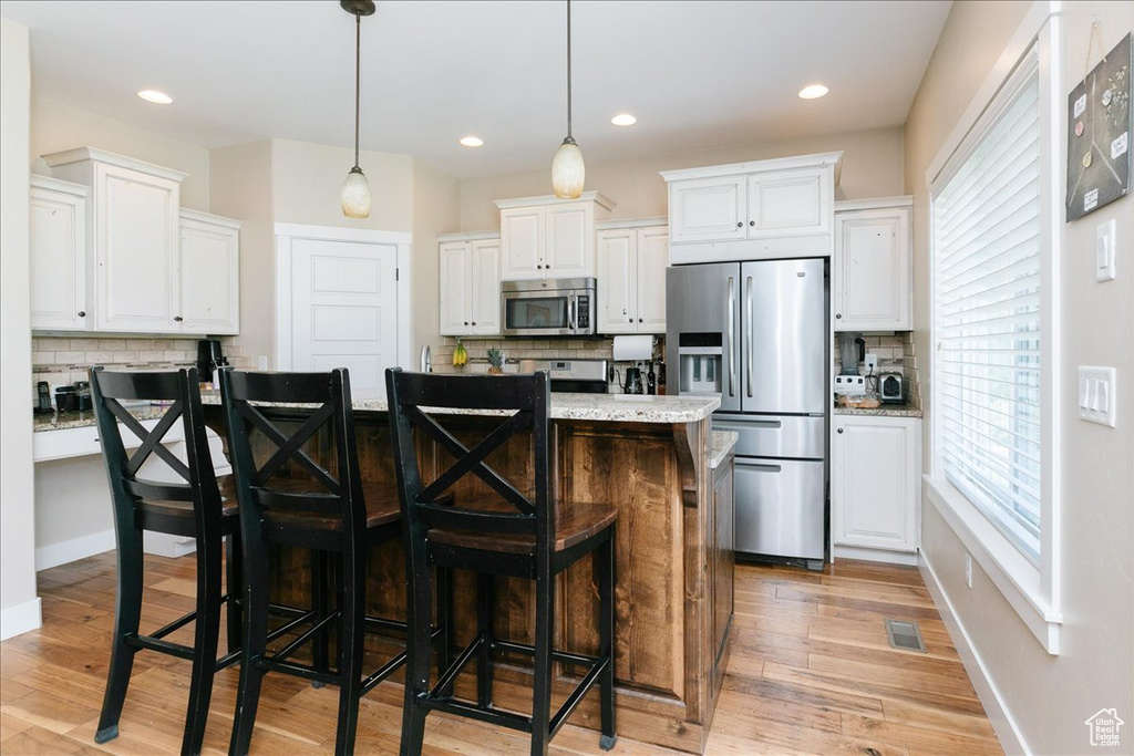 Kitchen featuring appliances with stainless steel finishes, backsplash, white cabinets, and recessed lighting