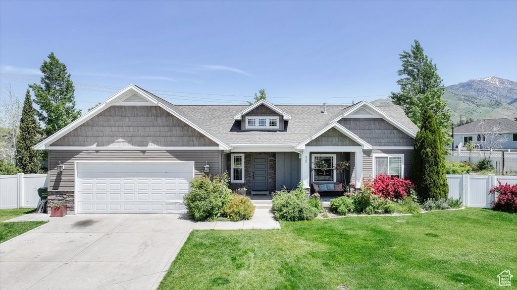 Craftsman house featuring stone siding, an attached garage, driveway, and a porch