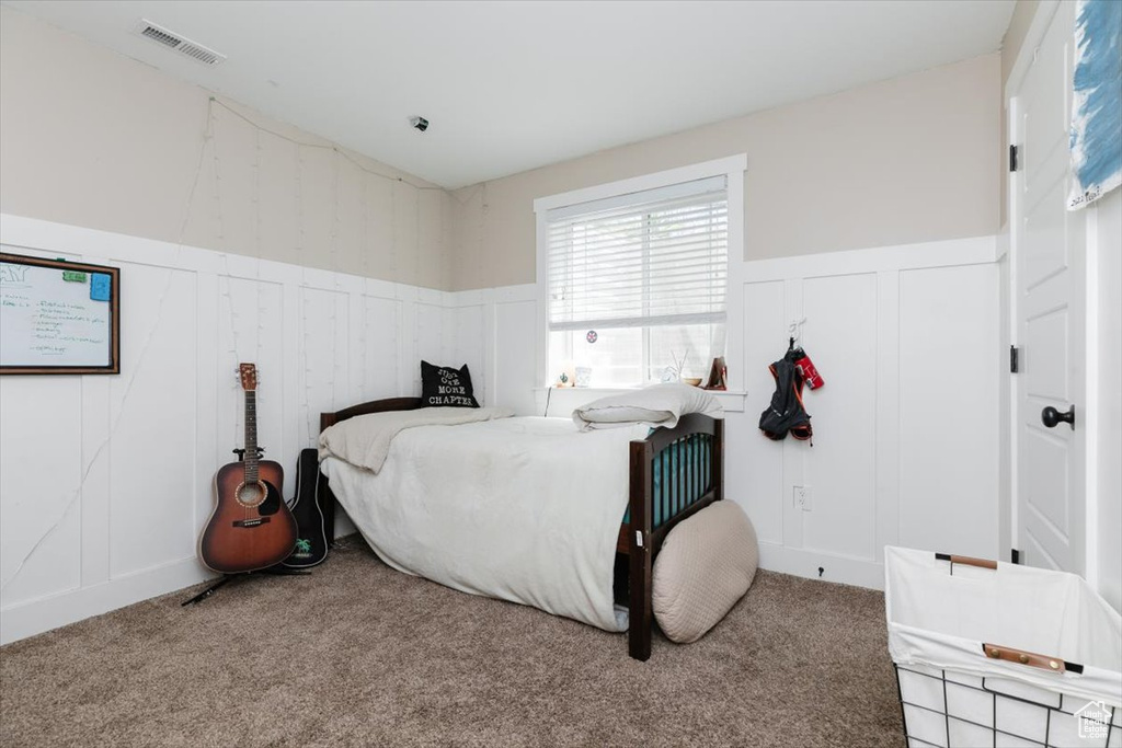 Carpeted bedroom with a decorative wall and wainscoting