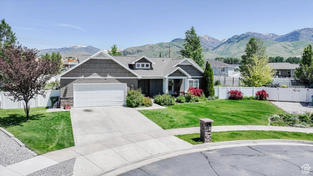 Craftsman-style home with an attached garage, a mountain view, driveway, and stone siding