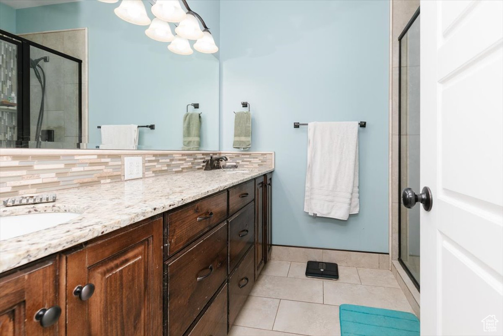 Full bath featuring a stall shower, tile patterned floors, double vanity, and backsplash
