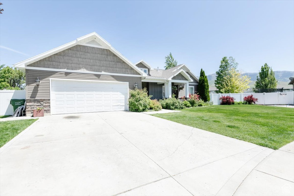 Craftsman-style house featuring a garage, driveway, and stone siding