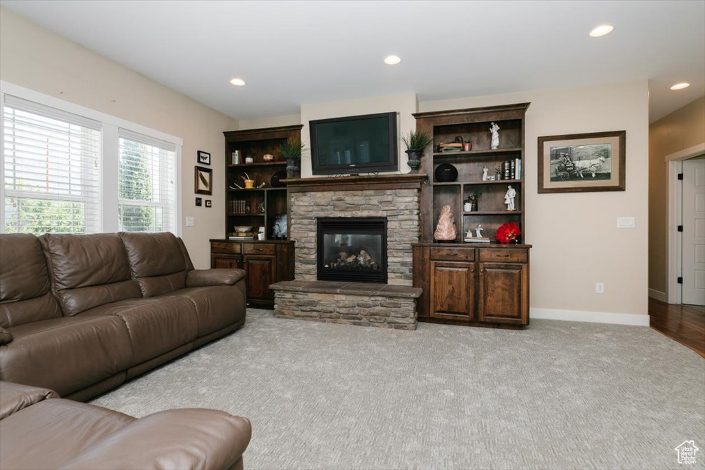 Living area featuring a stone fireplace, carpet, recessed lighting, and baseboards
