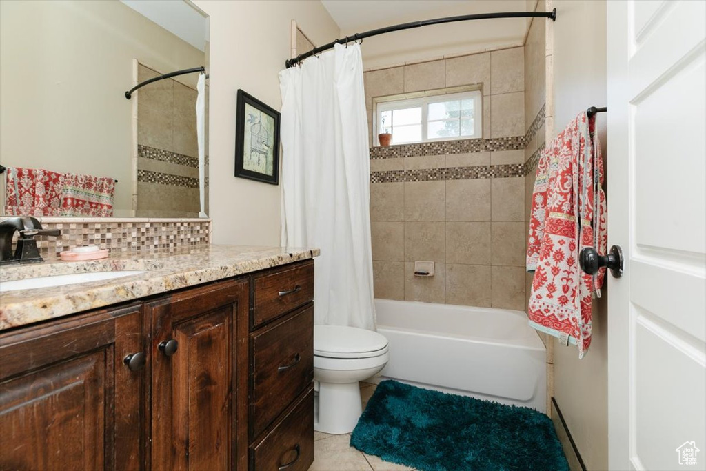 Full bathroom with vanity, shower / tub combo with curtain, toilet, tile patterned floors, and decorative backsplash
