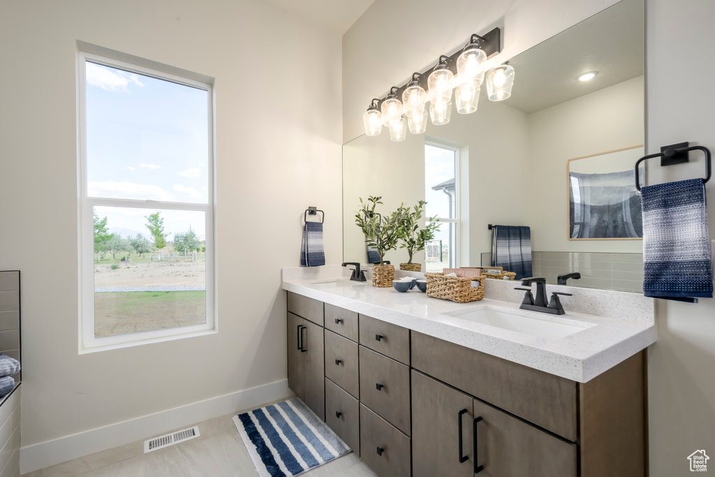 Full bathroom with double vanity, plenty of natural light, and baseboards