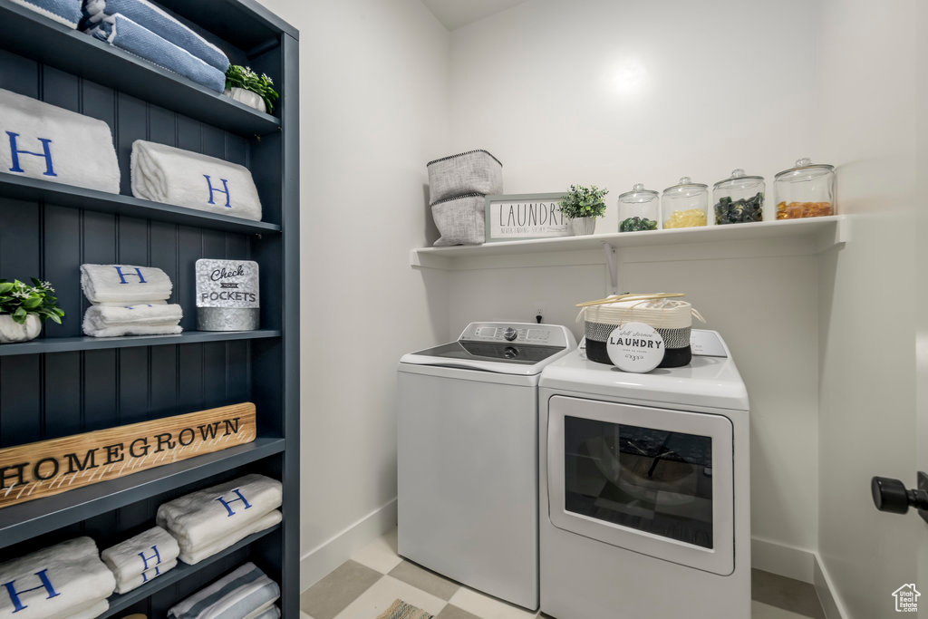 Laundry room featuring washing machine and clothes dryer, baseboards, and tile patterned floors