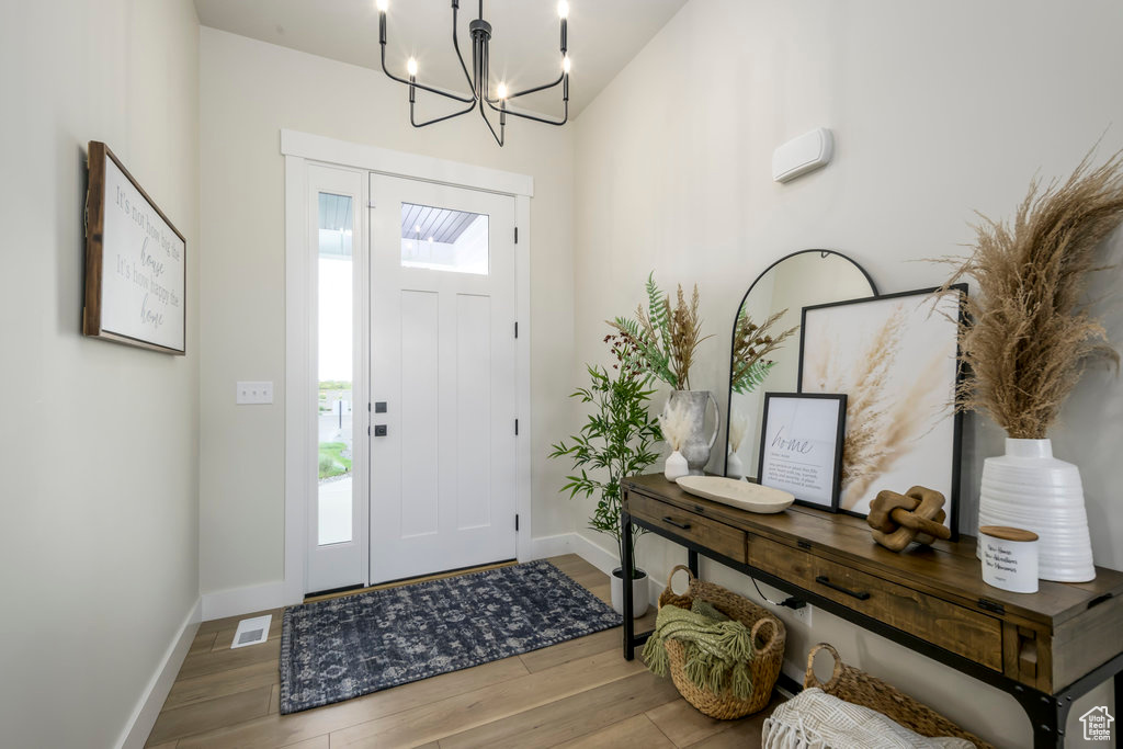 Foyer entrance with wood finished floors, baseboards, and a chandelier