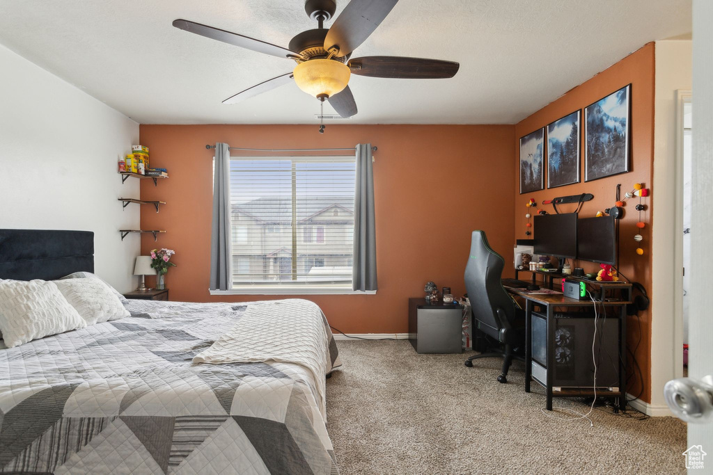 Carpeted bedroom featuring a ceiling fan, baseboards, and a desk