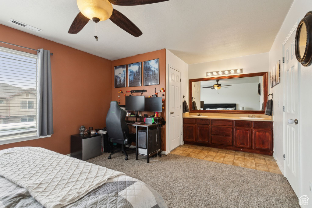 Bedroom featuring light colored carpet, a sink, ensuite bath, an office area, and light tile patterned flooring