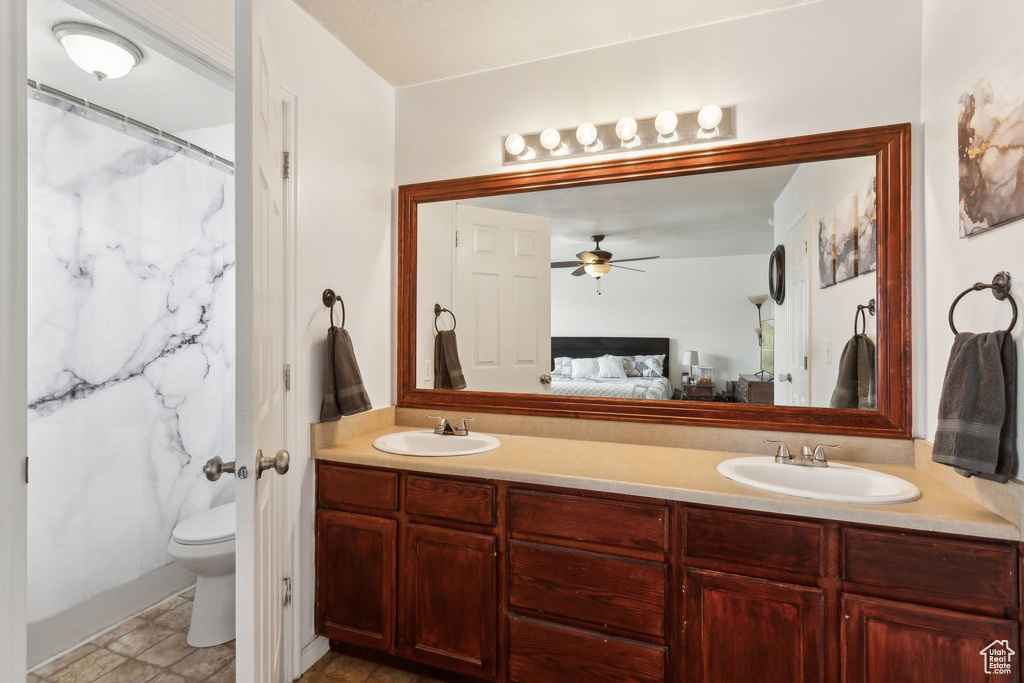 Ensuite bathroom with double vanity, toilet, and ceiling fan