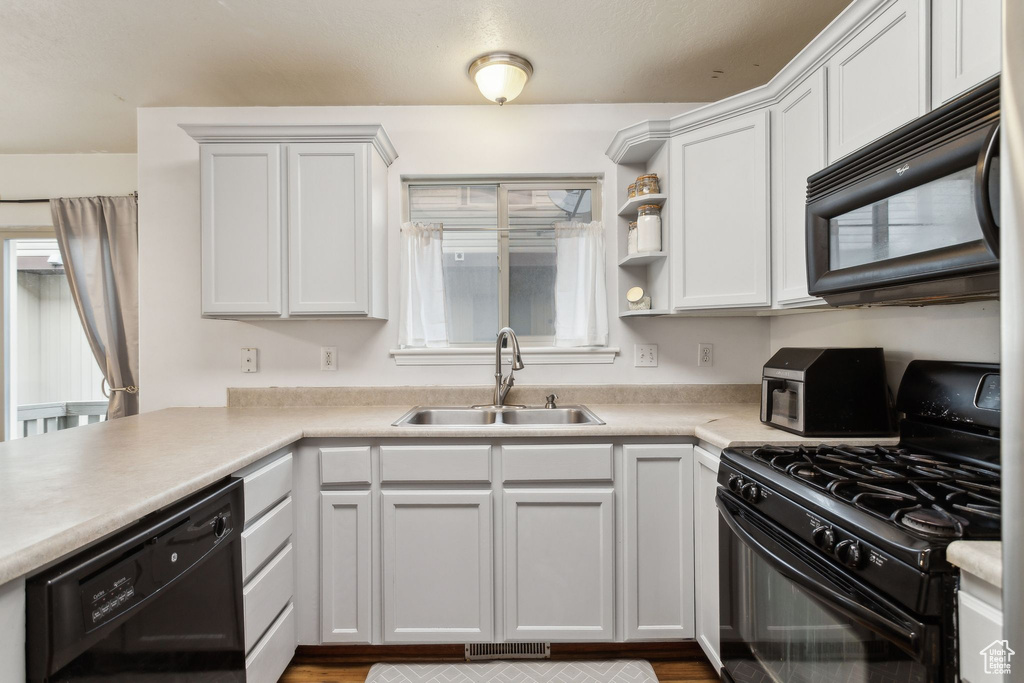 Kitchen with black appliances, a sink, light countertops, white cabinets, and open shelves