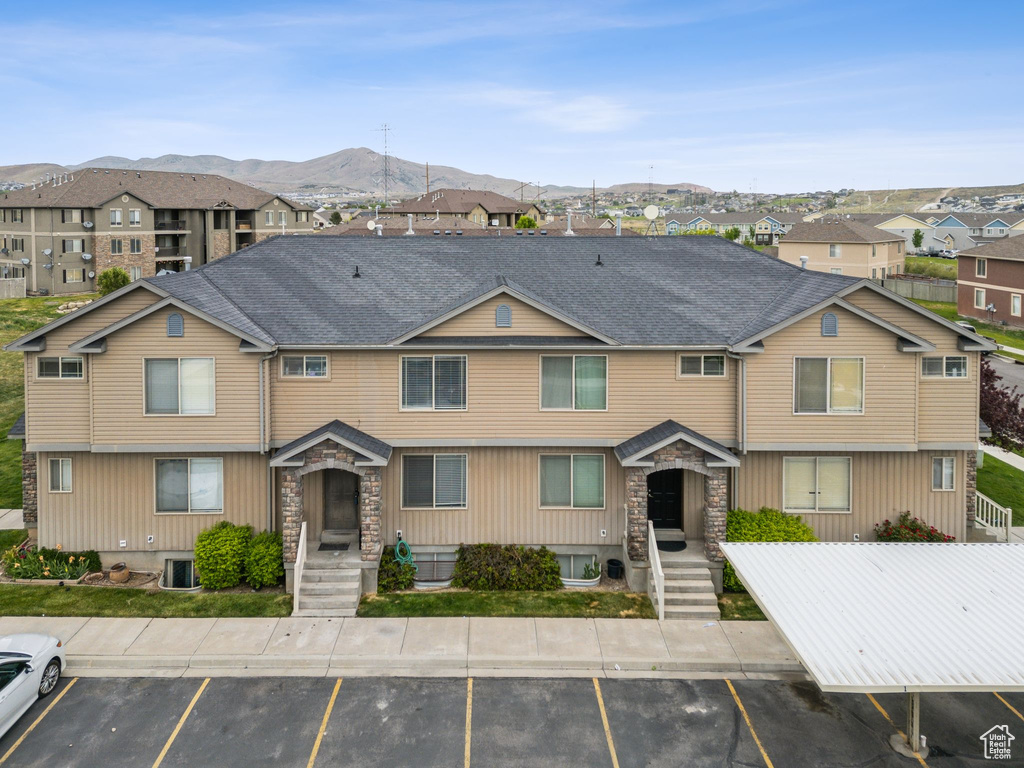 View of front of house featuring uncovered parking, stone siding, a mountain view, and a residential view